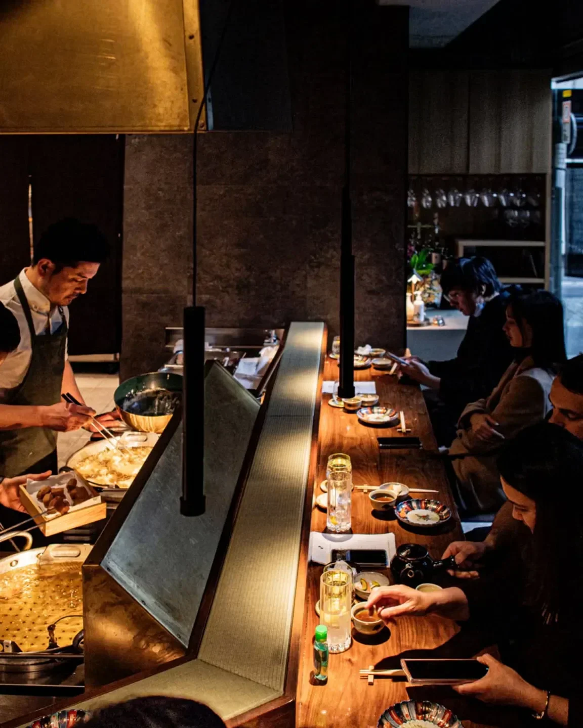 Inside HACO Sydney restaurant, guests enjoying dining experience while chef prepares food.