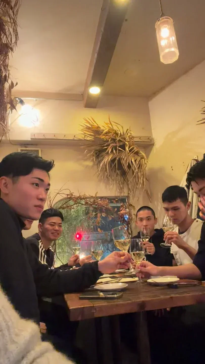 Group of friends toasting at Hatsune Sushi in Tokyo, enjoying dinner and wine.
