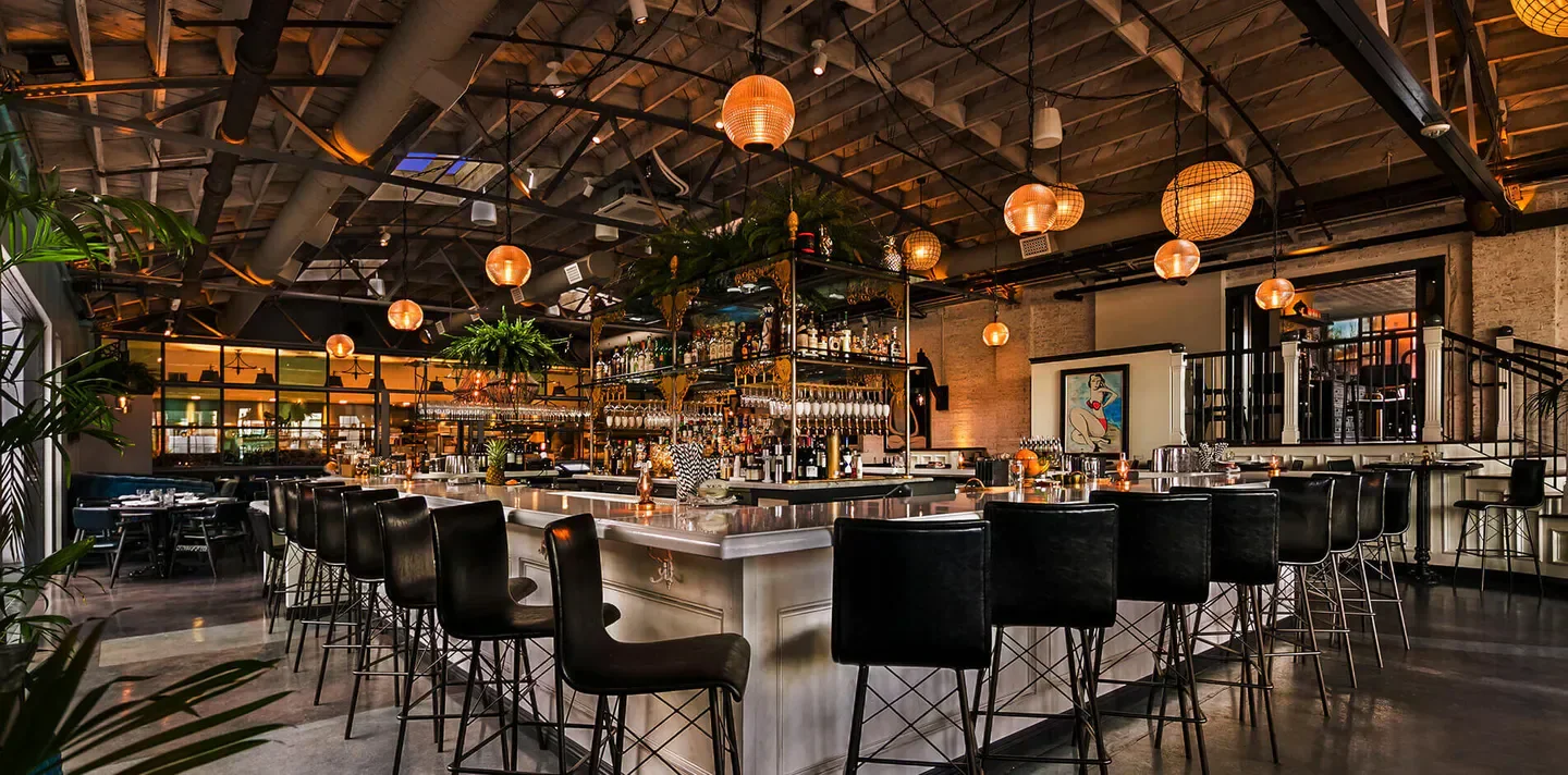 Interior bar at Herb & Wood restaurant in San Diego with hanging lights and stylish decor
