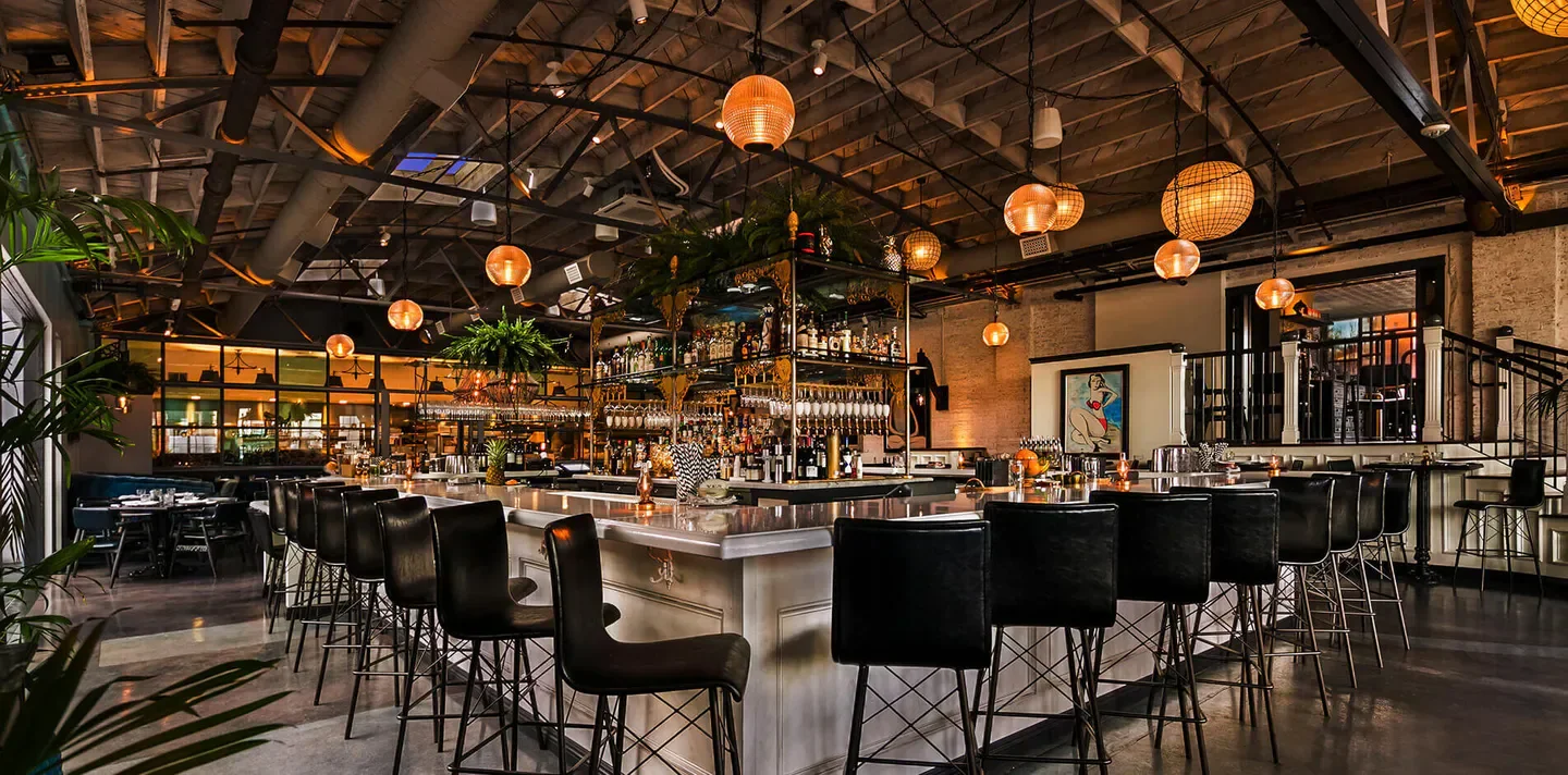 Interior bar at Herb & Wood restaurant in San Diego with hanging lights and stylish decor
