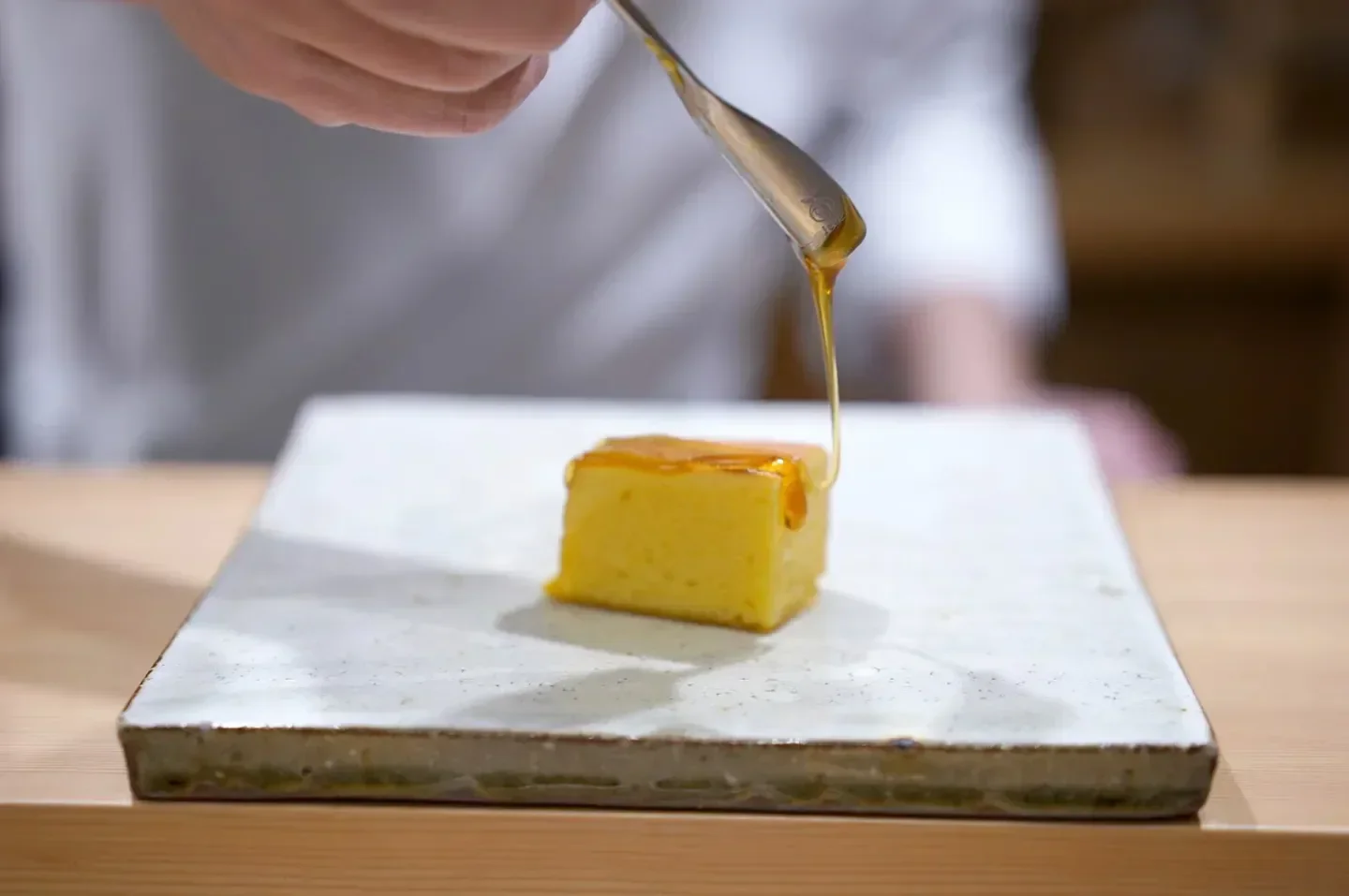 Chef drizzling honey on dessert at Higashiazabu Amamoto restaurant in Tokyo.