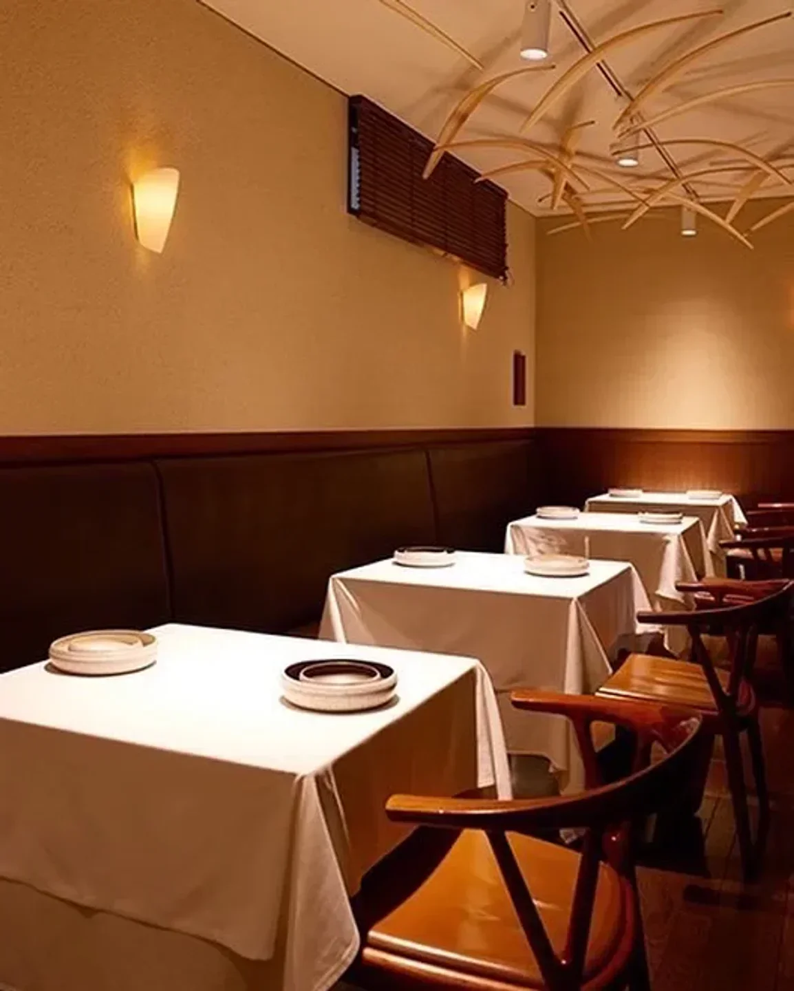Interior of HOMMAGE restaurant in Tokyo, showcasing elegant dining tables and unique lighting.