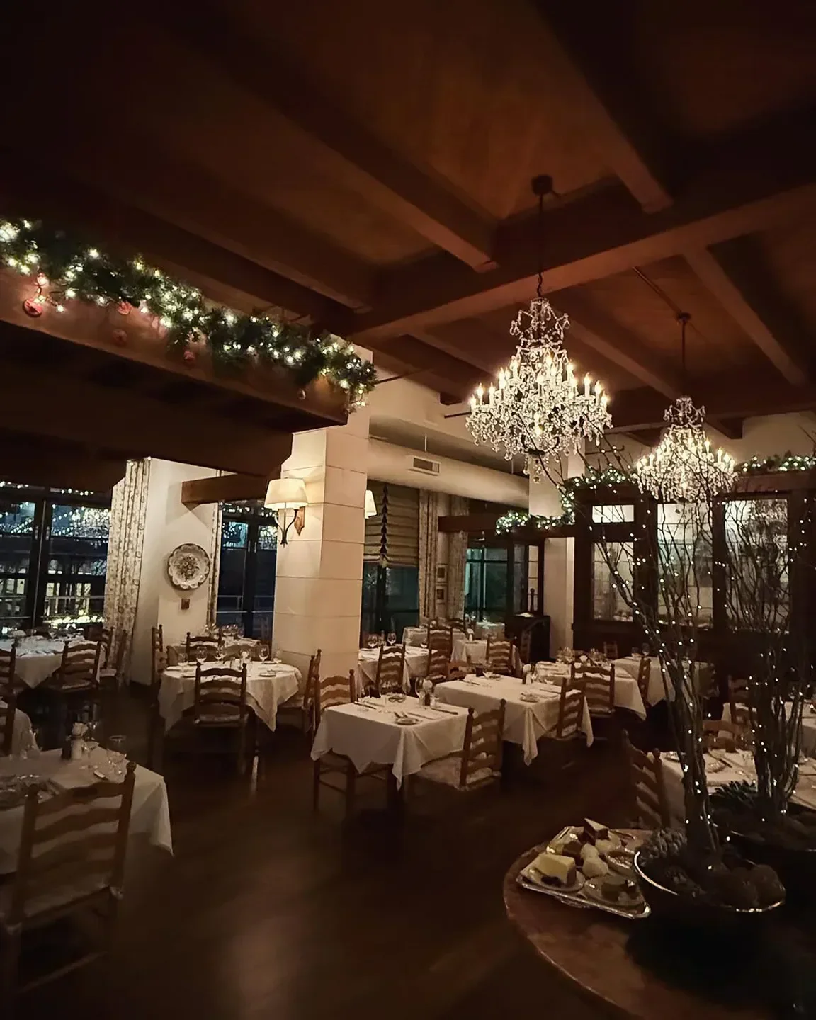 Cozy dining room at Il Terrazzo Carmine in Seattle, with chandeliers and decorated for the holidays.