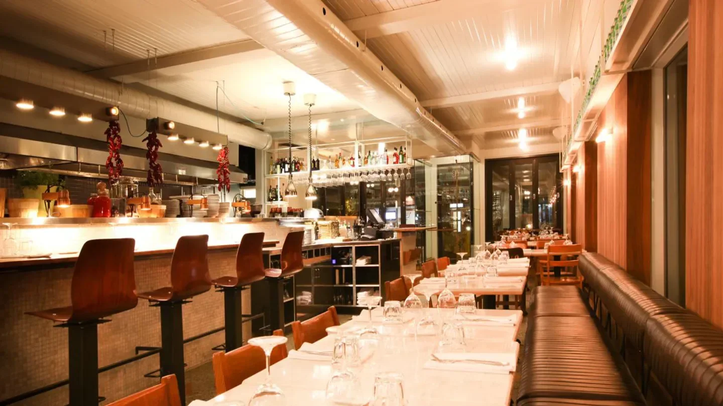 Cozy interior of Impasto restaurant in Montreal, featuring bar seating and dining tables.