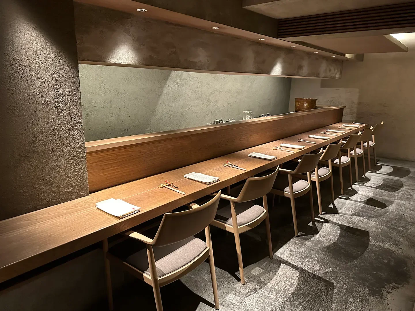 Minimalist interior seating at Ippei Hanten restaurant in Tokyo, featuring wood and neutral tones.