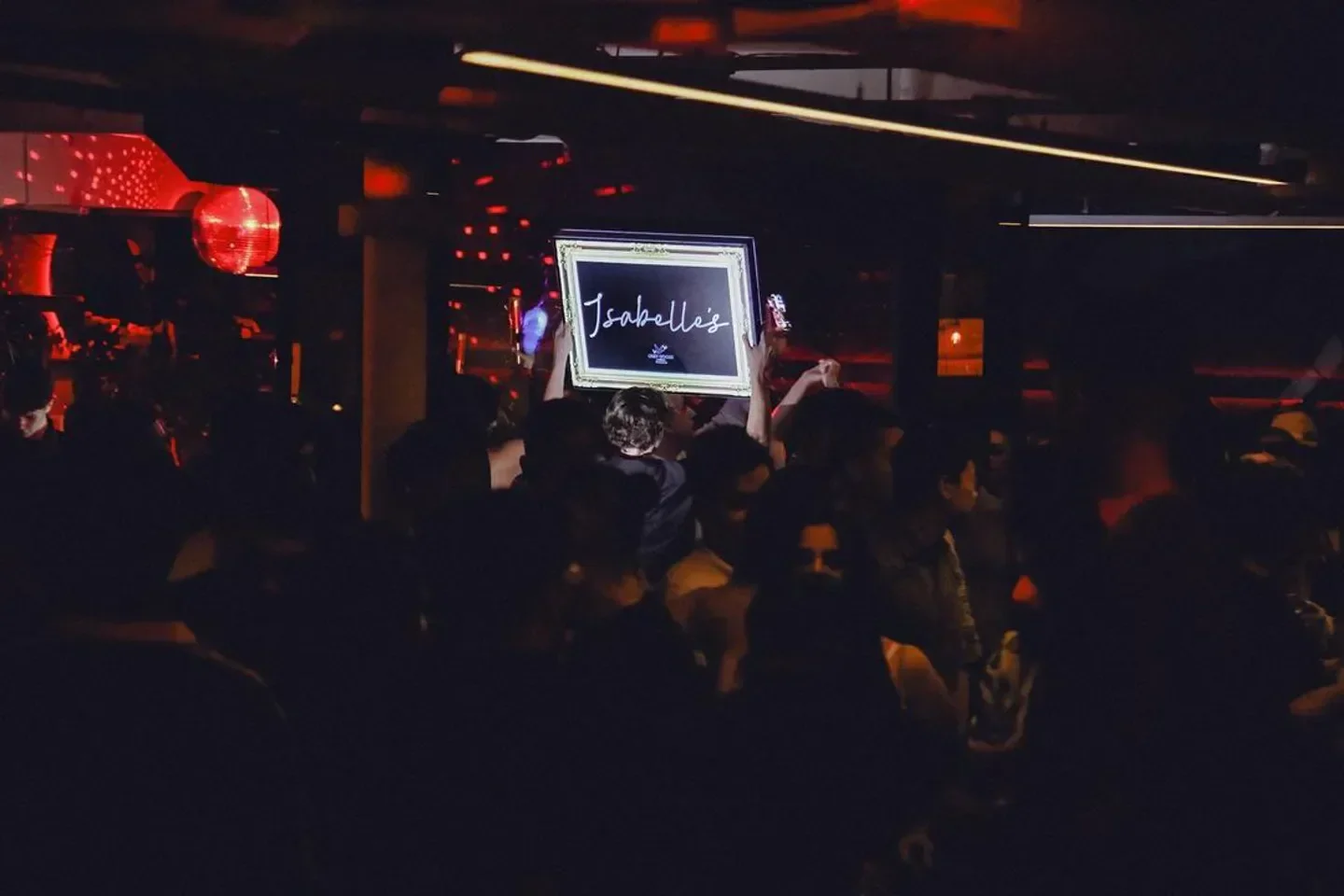 Party scene at Isabelle's nightclub in Toronto with sign held up by the crowd