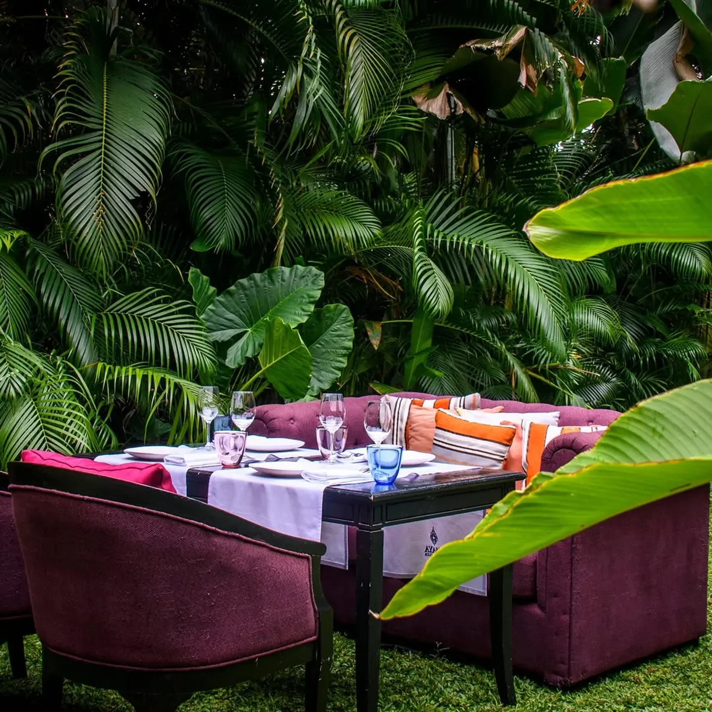 Elegant outdoor dining at Issaya Siamese Club in Bangkok, surrounded by lush greenery.