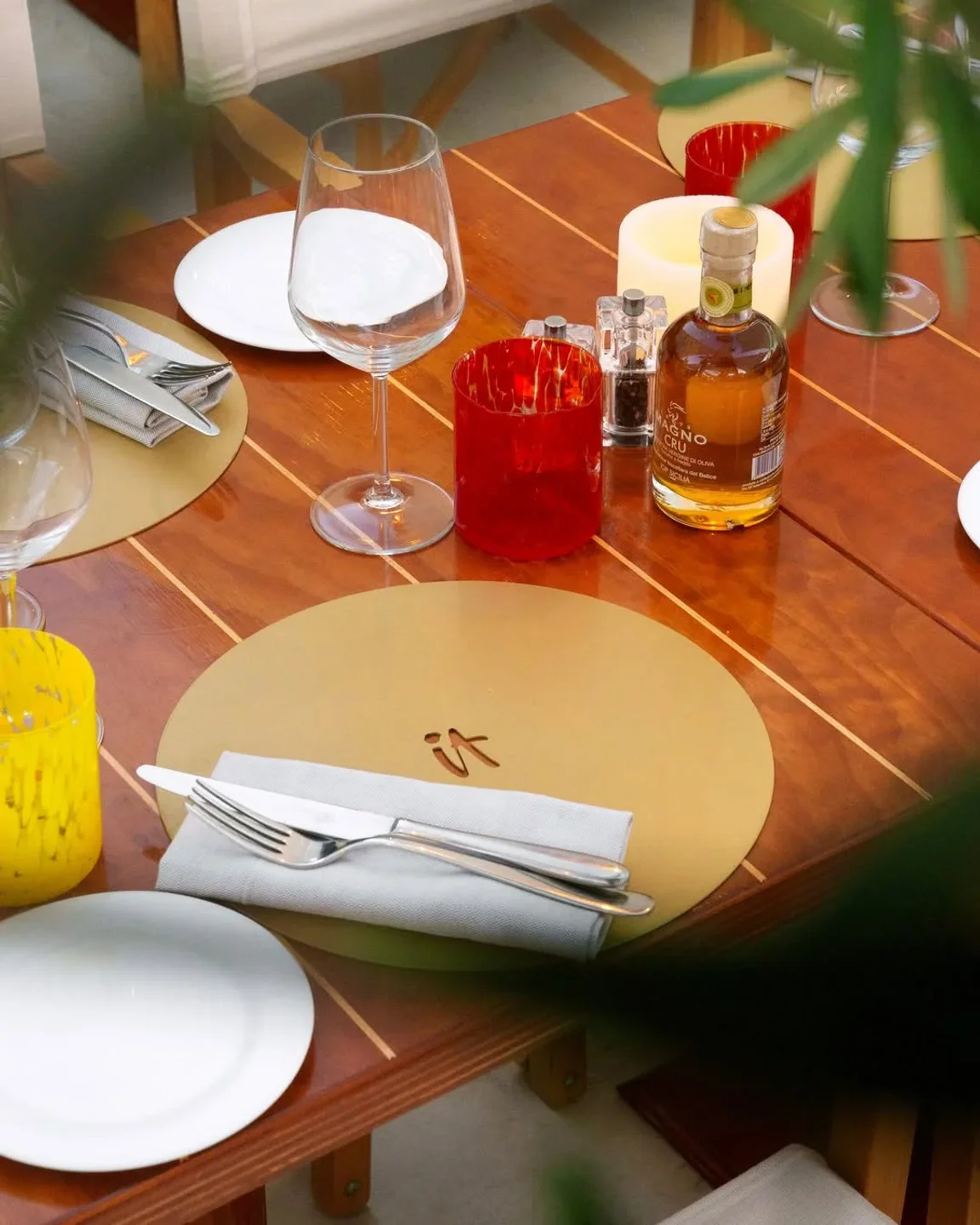 Elegant table setting at IT restaurant in Porto Cervo, IT with gold placemats and modern cutlery.