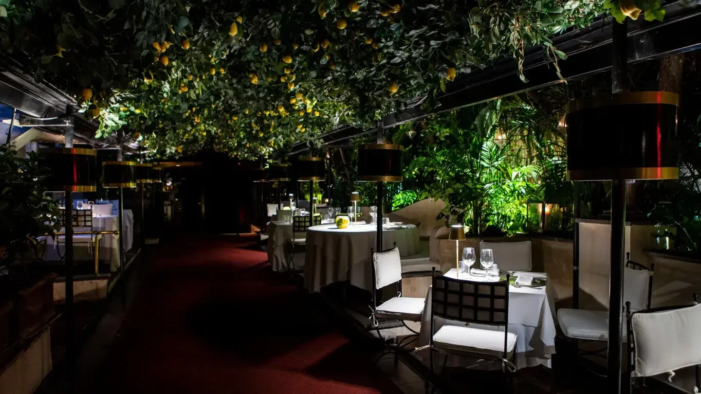 Tables under lemon tree at Jackie O' nightclub in Rome at night.