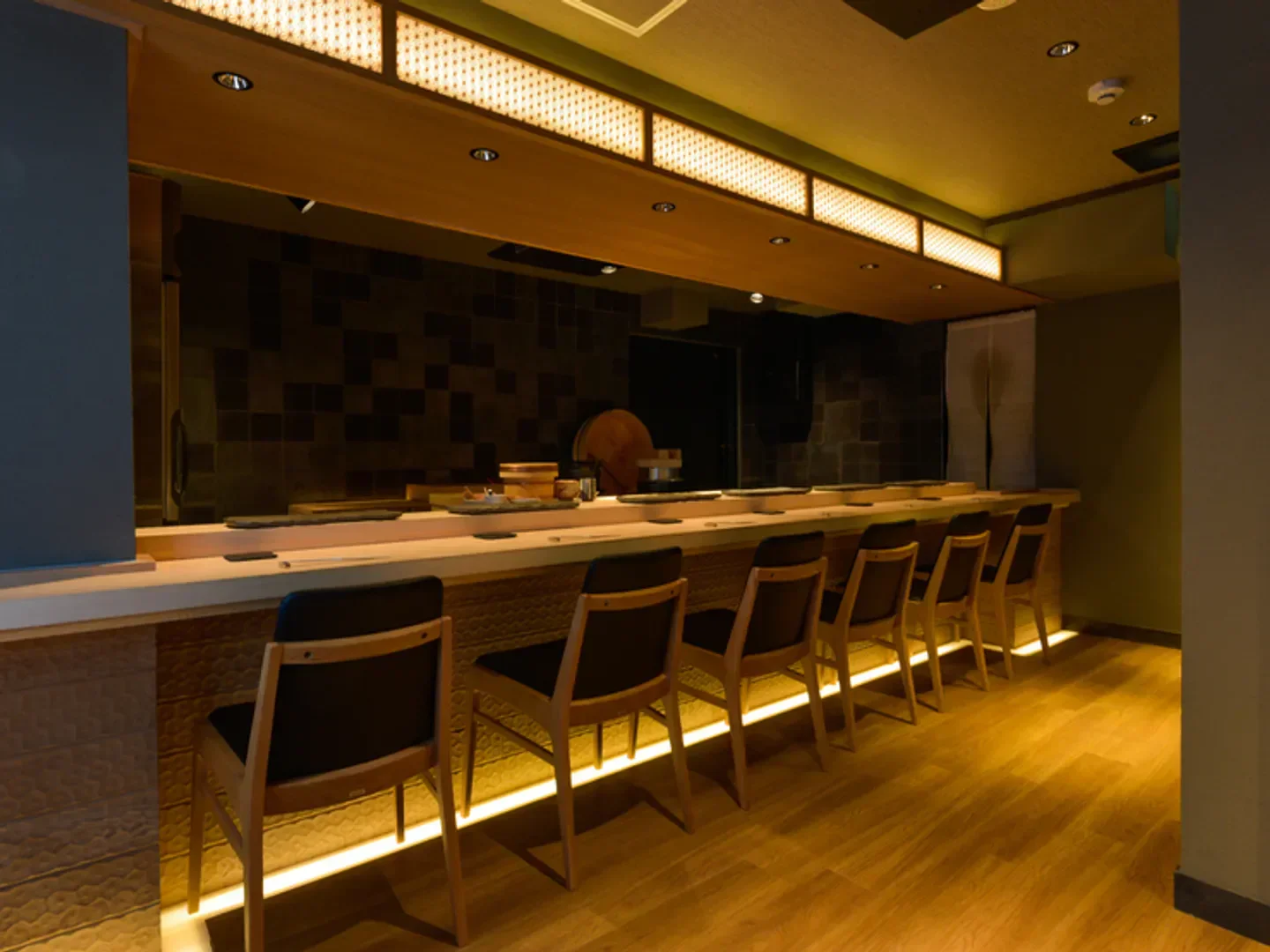 Interior of Jukuseizushi Yorozu in Tokyo, featuring sushi bar and seating area.