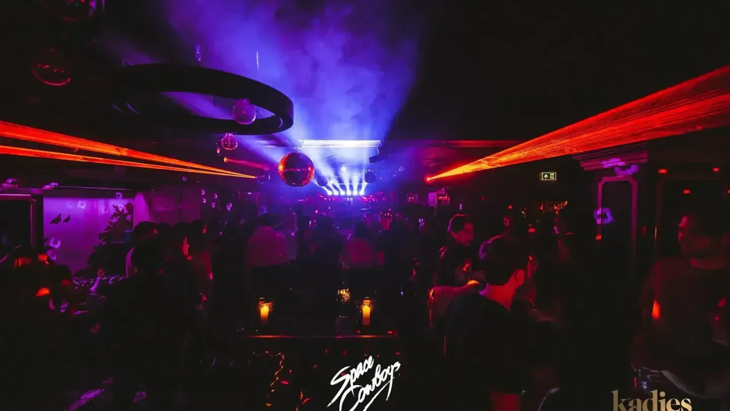 Inside Kadies Club in London, with laser beams and dancing people, a lively nightclub.