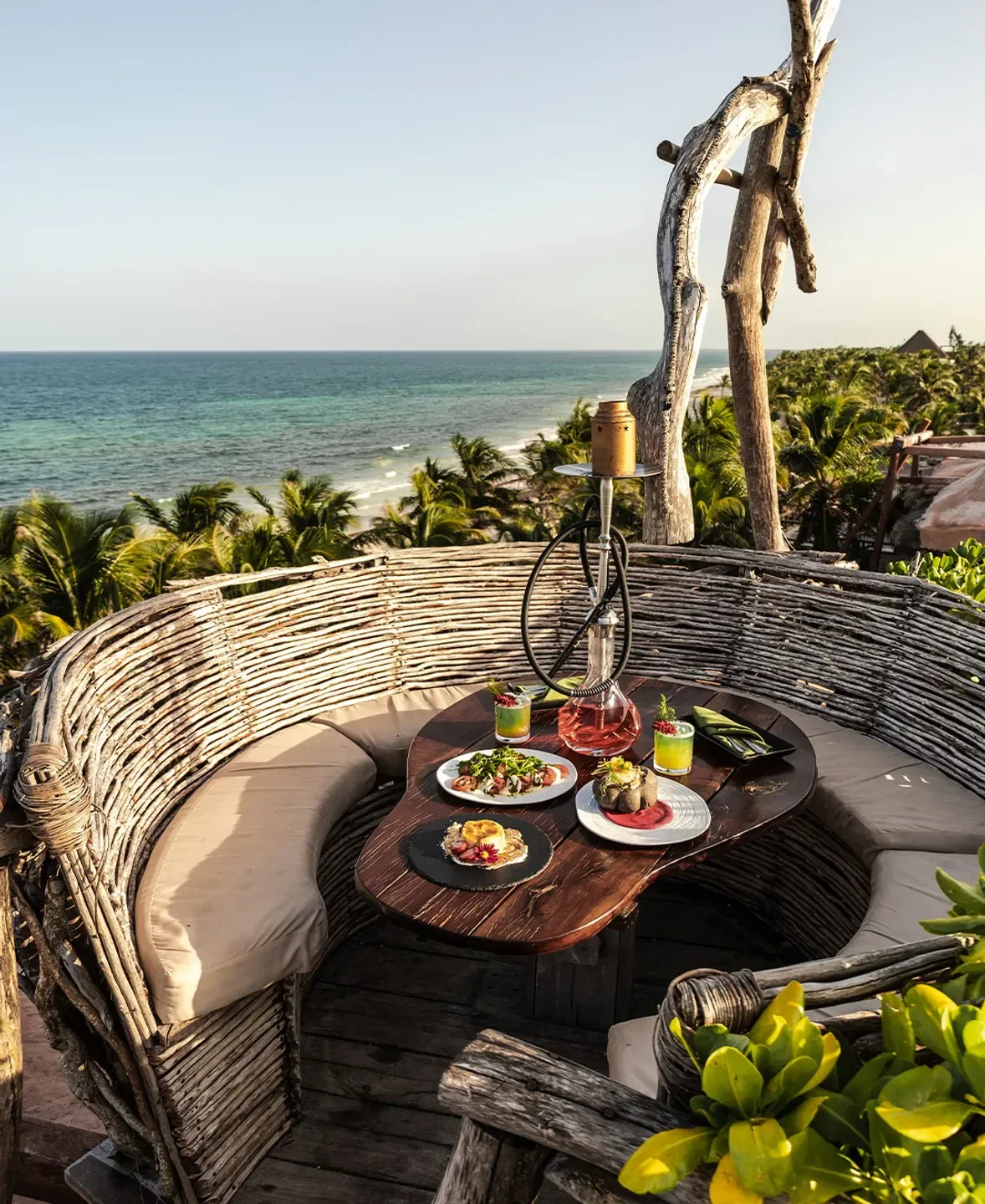 Cozy dining setting at Kanan restaurant in Tulum with ocean view and hookah.