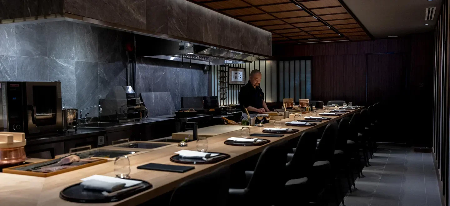 Interior of Kappo Sato restaurant in Toronto, with chef preparing food at the counter.