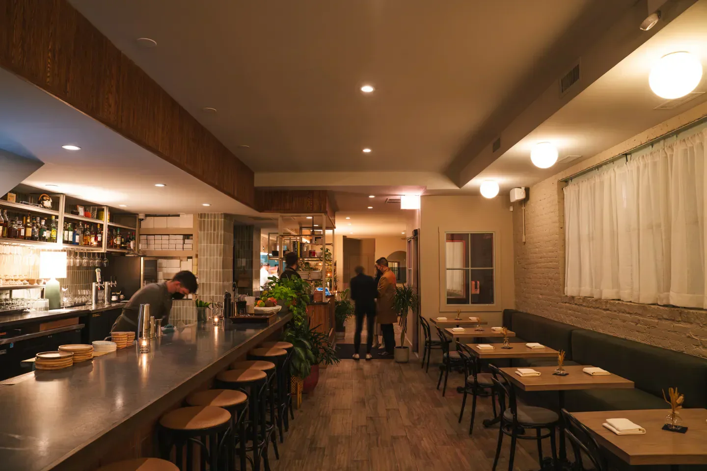 Interior of Kasama restaurant in Chicago with bar, tables, and cozy lighting.