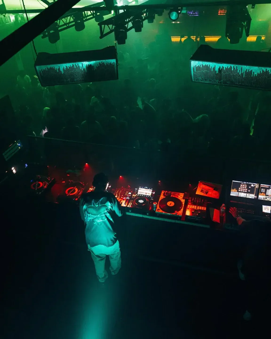 DJ spinning at Kingdom nightclub in Austin, green neon lights and party atmosphere.