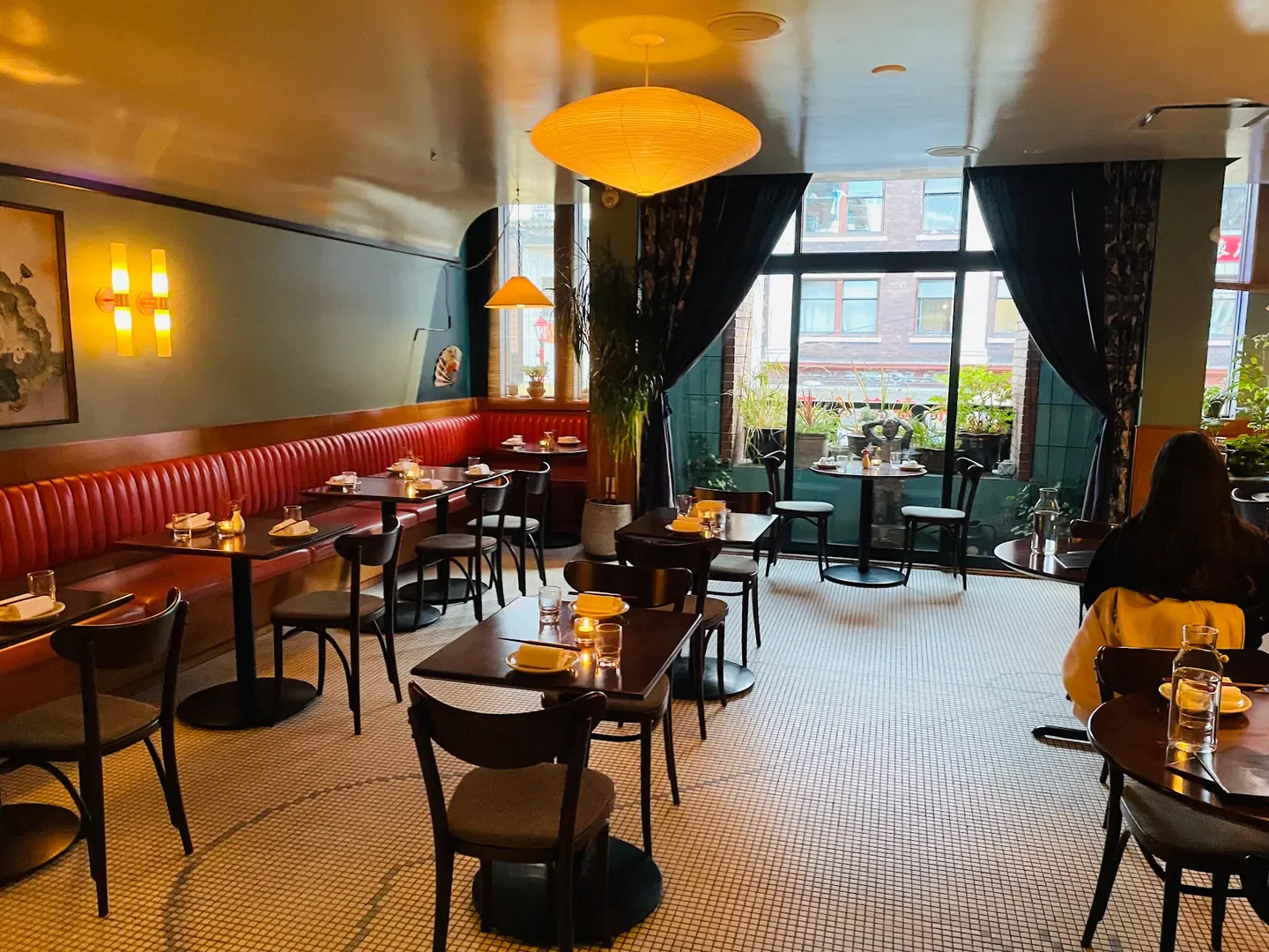 Interior of Kissa Tanto restaurant in Vancouver with tables, chairs, and plants.