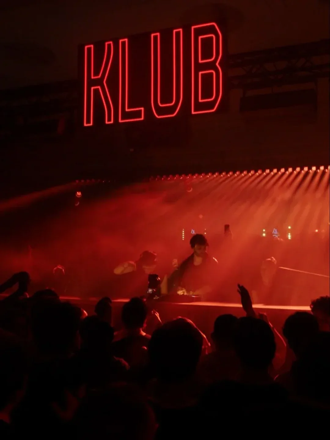Red neon KLUB sign illuminates energetic crowd at a lively nightclub in Cannes