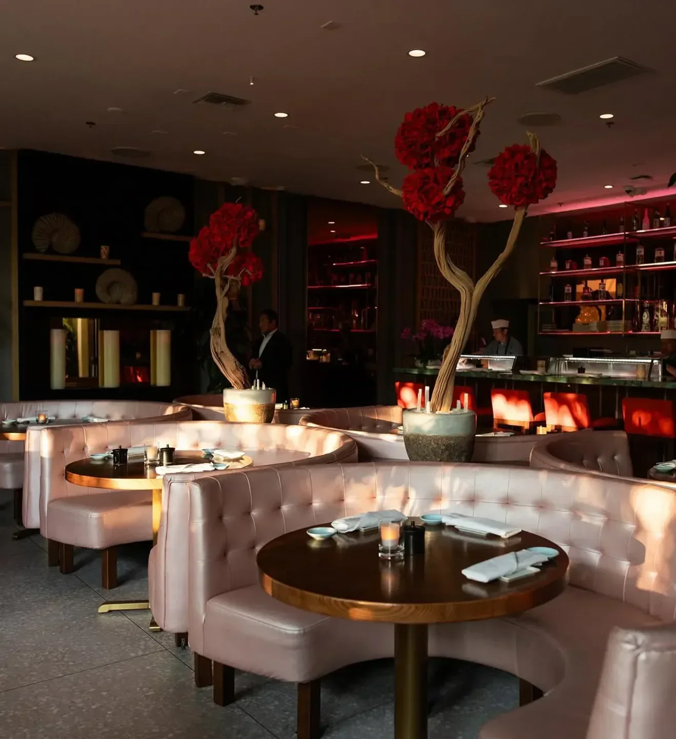 Interior of Koi Los Angeles restaurant with pink booths, tables, and floral decor.