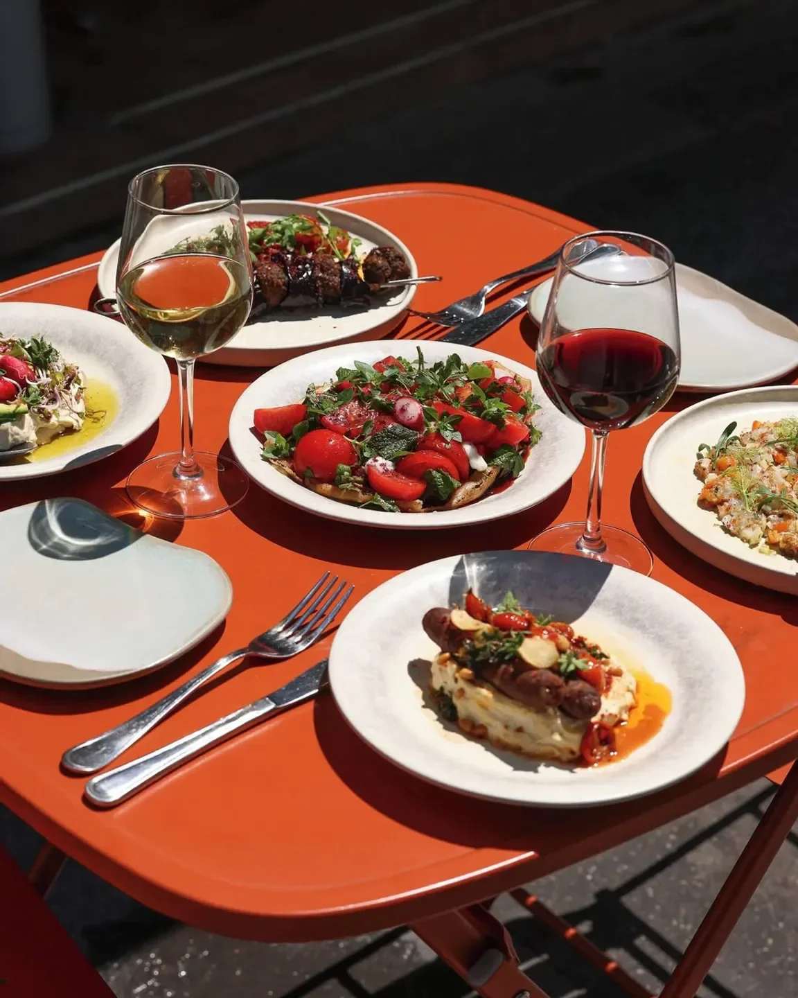 Delicious dishes and wine on an orange table at Kubri restaurant in Paris.