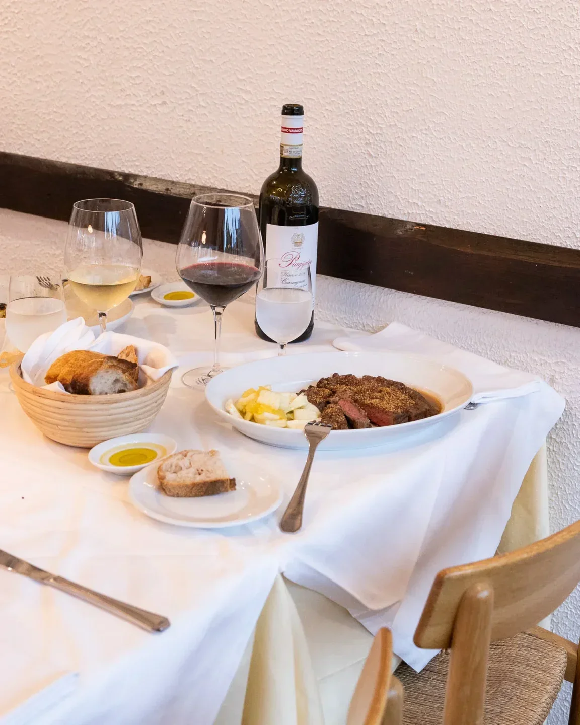 Table setting at La Buca Degli Artisti restaurant in Copenhagen with food and wine.