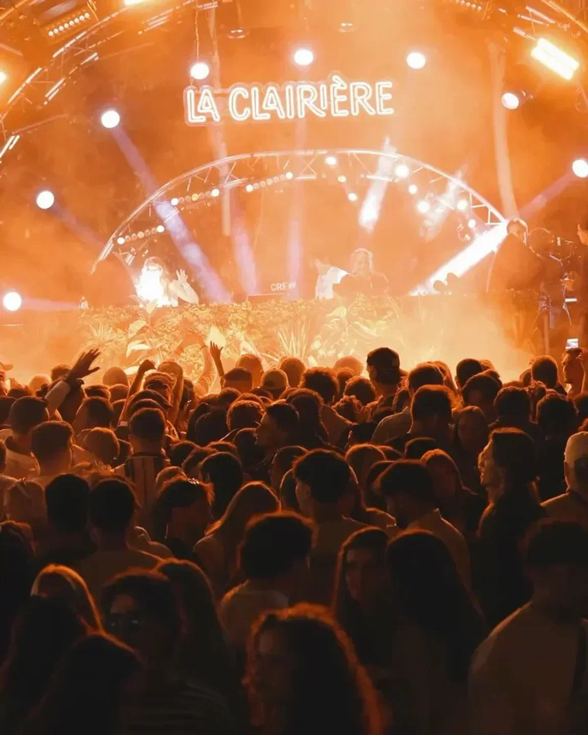 Energetic crowd at La Clairière nightclub in Paris, dancing under stage lights.