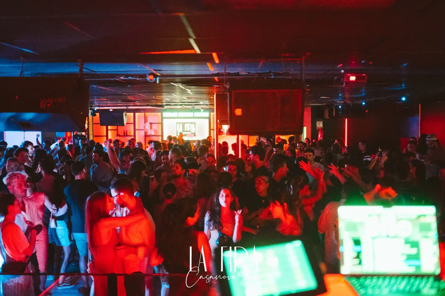 Energetic crowd partying at La Fira Casanova nightclub in Barcelona with vibrant lights