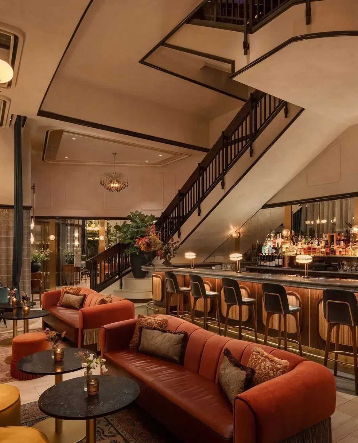 Stylish interior of La Padrona Boston, featuring bar, staircase, and seating area.