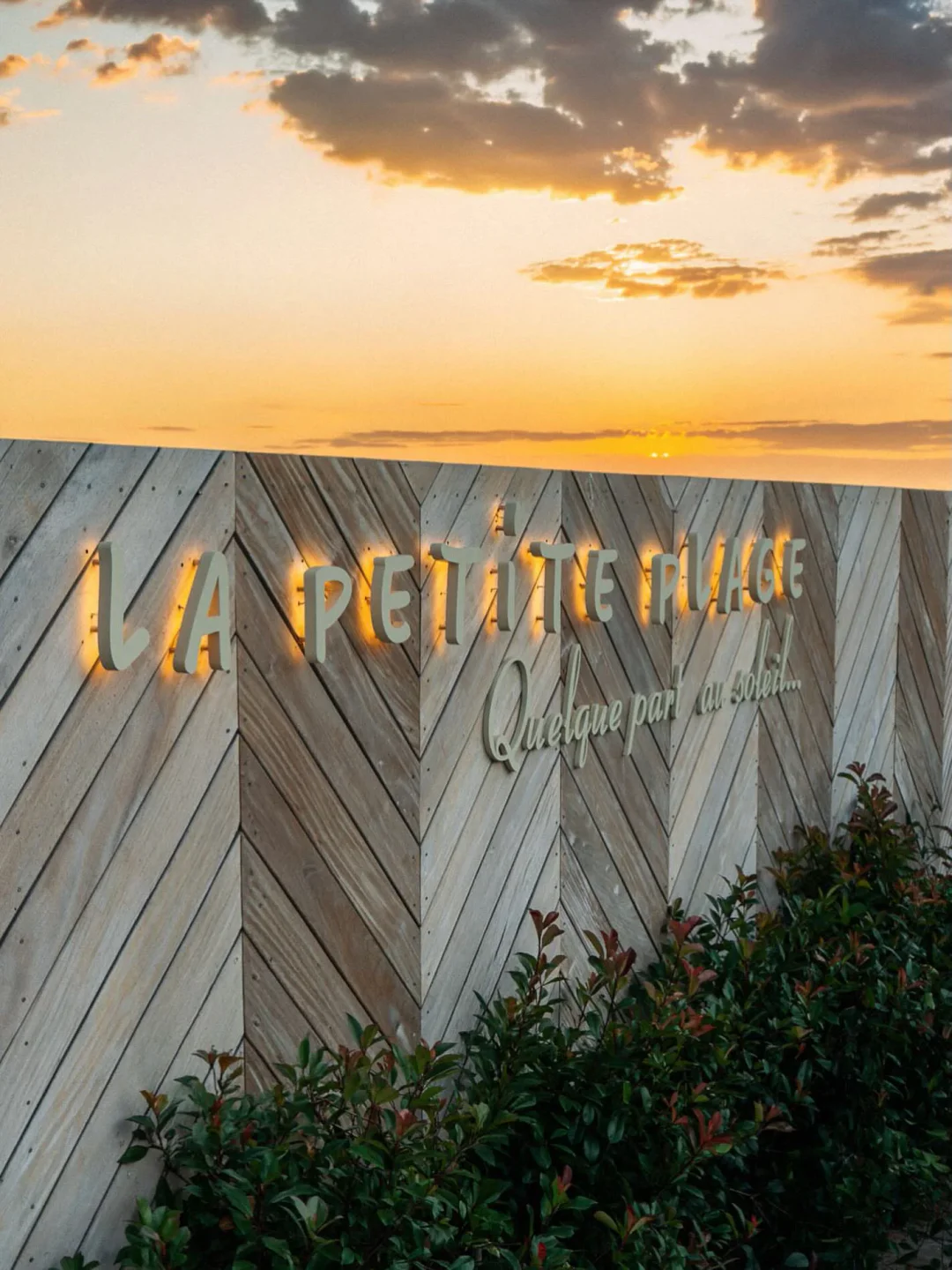 La Petite Plage restaurant exterior sign at sunset with wooden accent wall in the city.