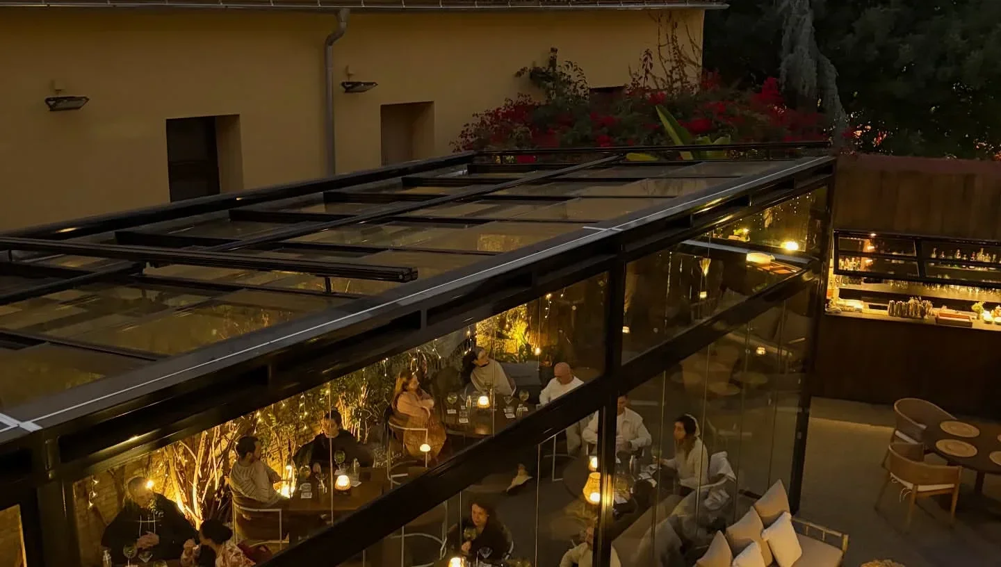 Outdoor dining at La Salita restaurant in Valencia, with glass enclosure and warm lighting.