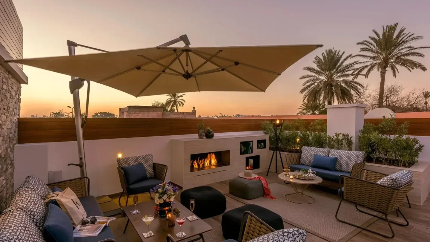 Rooftop terrace at La Terrasse de la Brillante in Marrakech at sunset with fireplace and palm trees