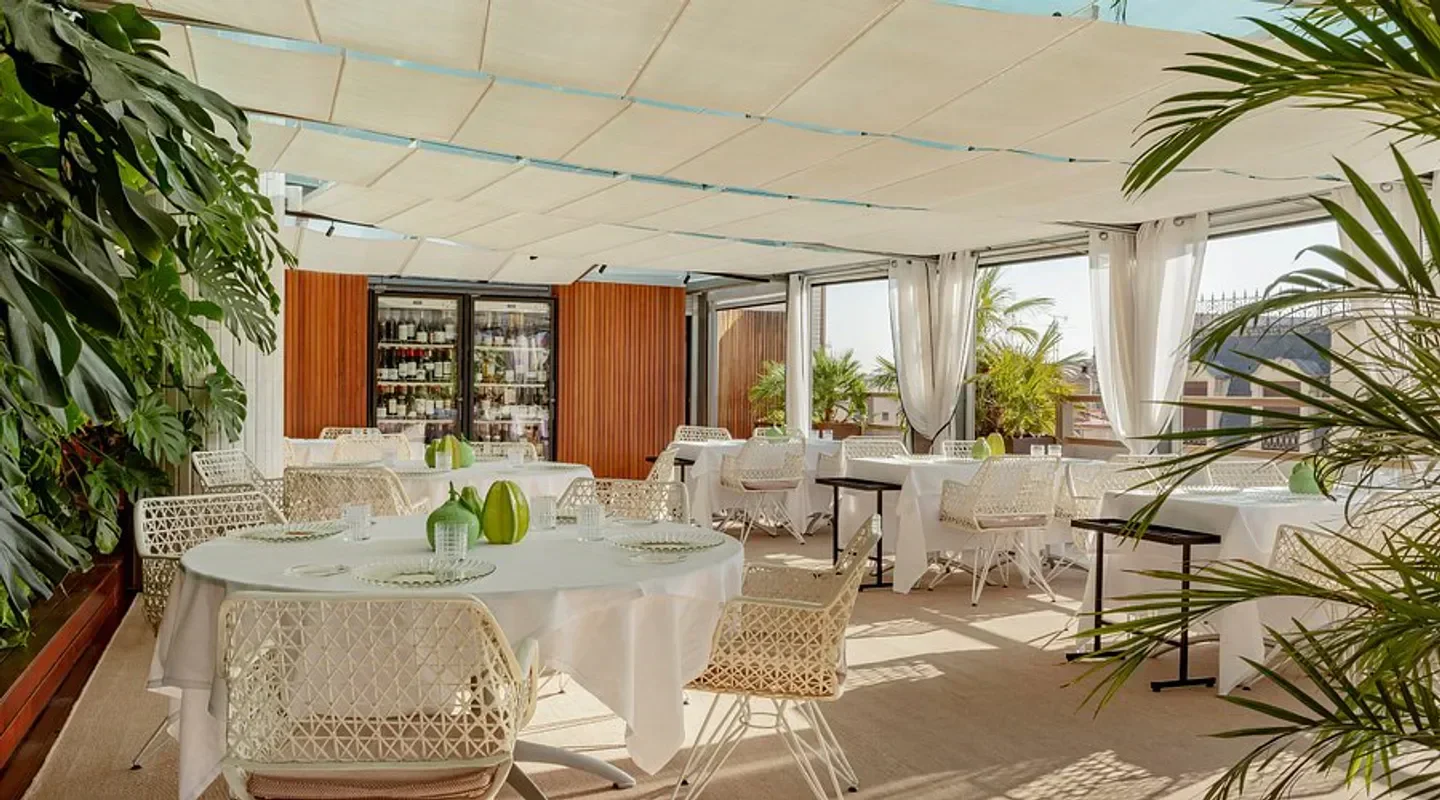 Elegant dining space at La Terraza del Claris restaurant in Barcelona, with lush greenery.