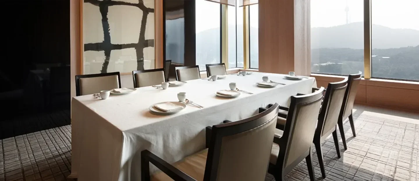 Elegant dining space at La Yeon restaurant in Seoul, with mountain views and table setting.