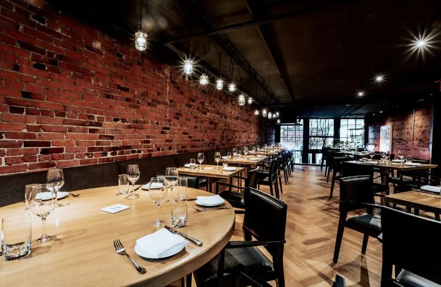 Interior dining space at L’Abattoir restaurant in Vancouver with brick walls and wood tables