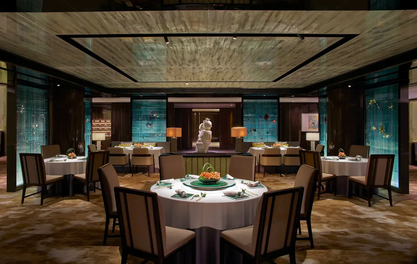 Elegant dining room at Lai Ching Heen restaurant in Hong Kong, with round tables.