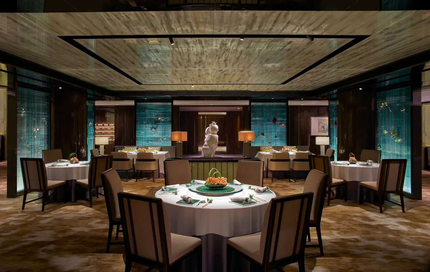 Elegant dining room at Lai Ching Heen restaurant in Hong Kong, with round tables.