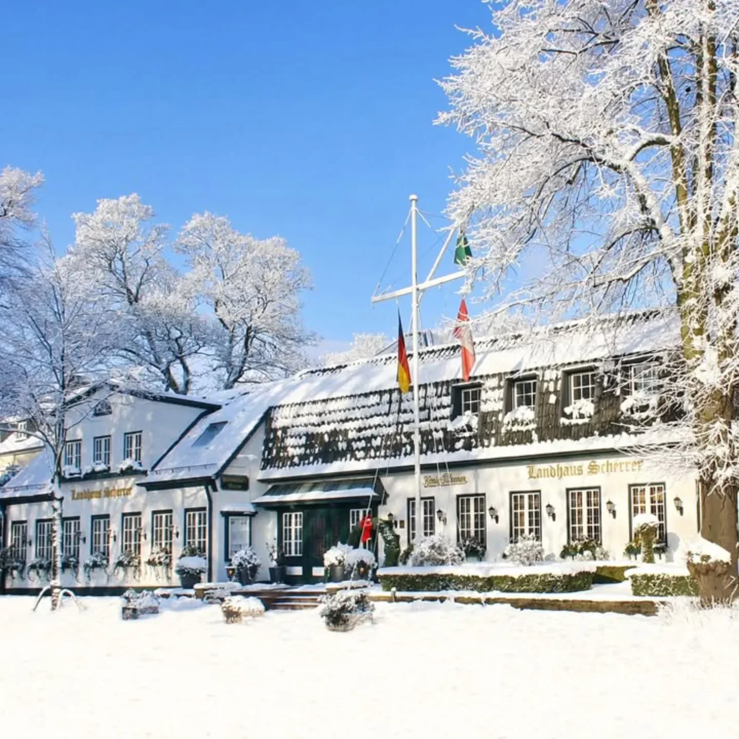 Winter wonderland scene at Landhaus Scherrer restaurant in Hamburg, Germany, covered in snow.