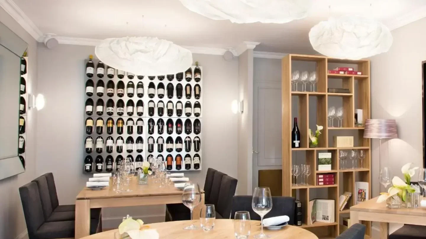 Elegant dining room at L'aparté restaurant in Geneva, with a wine display.