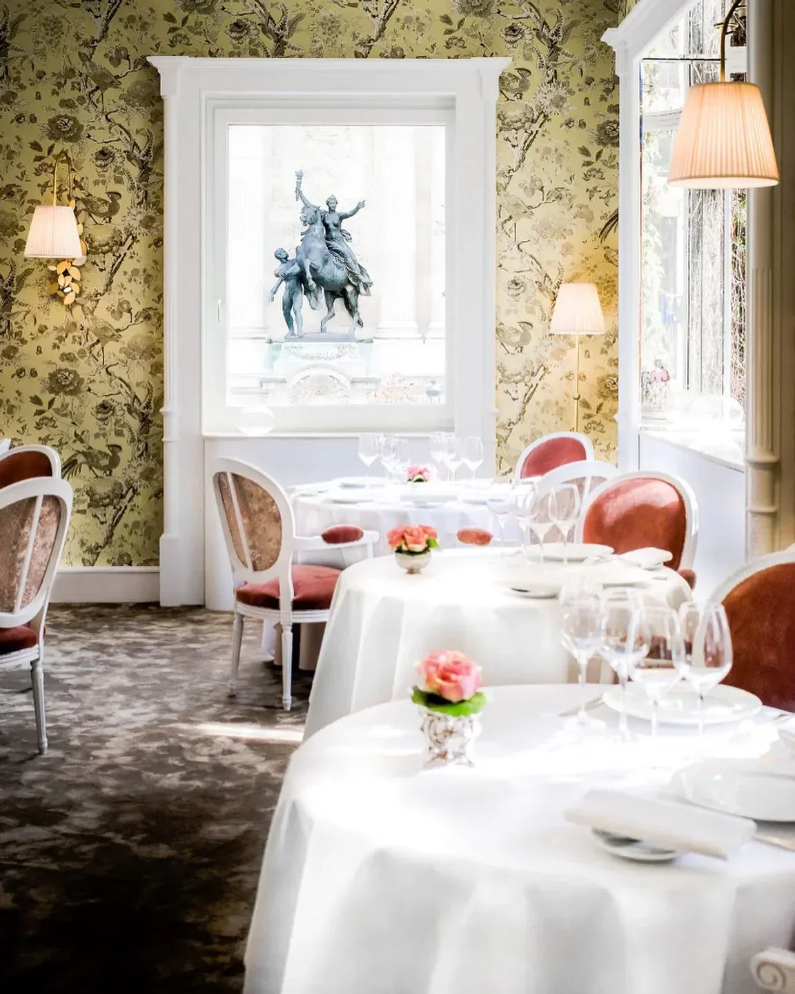 Elegant interior of Lasserre in Paris, featuring floral wallpaper and fine dining.