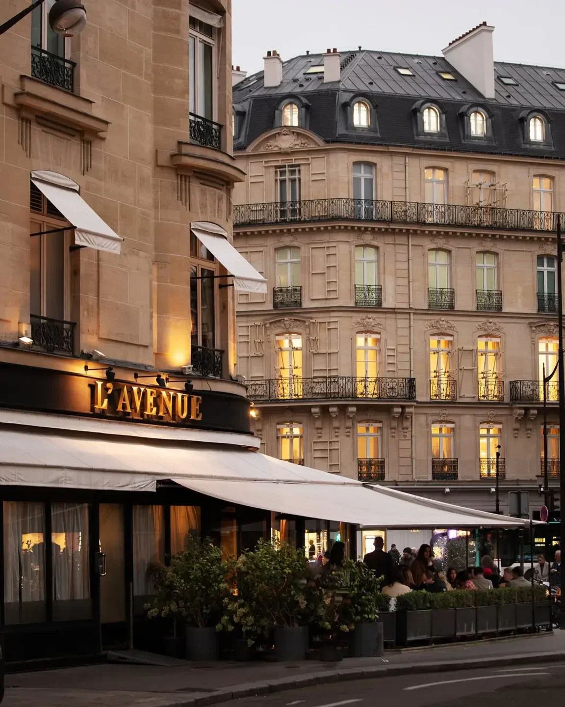 Outdoor seating at L'Avenue restaurant in Paris, showcasing elegant Parisian architecture.