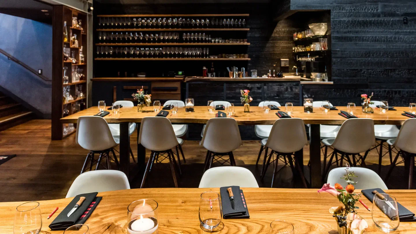 Interior of Lazy Bear restaurant in San Francisco with long tables and modern decor.