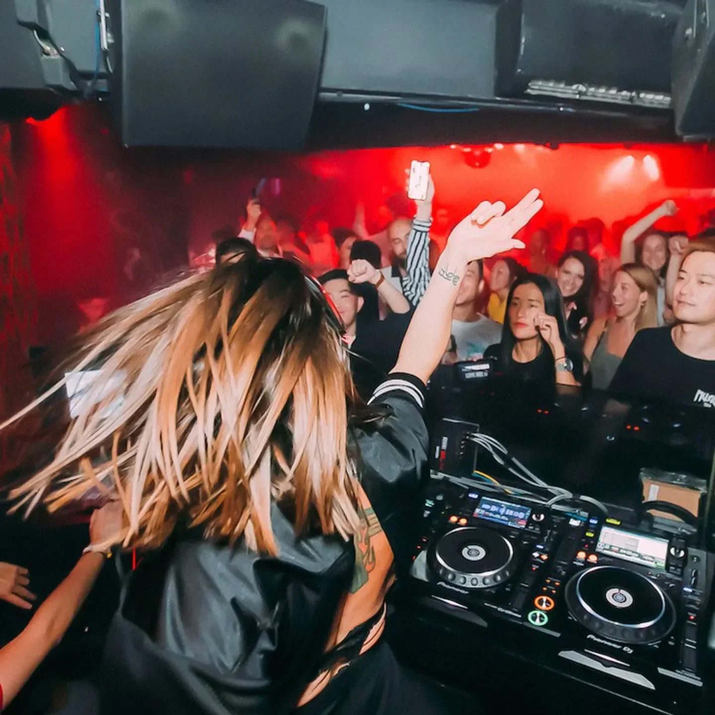 Energetic DJ at Le Baron Shanghai nightclub, entertaining a lively crowd with red lighting