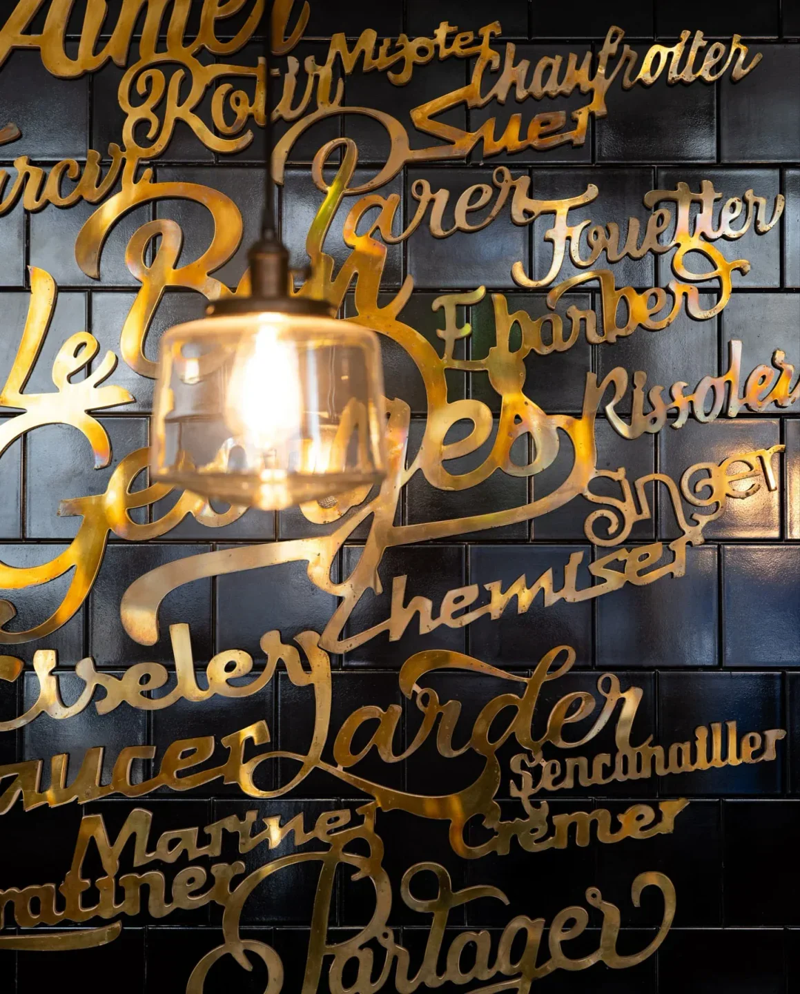 Interior design at Le Bon Georges restaurant in Paris with golden lettering and a lamp.