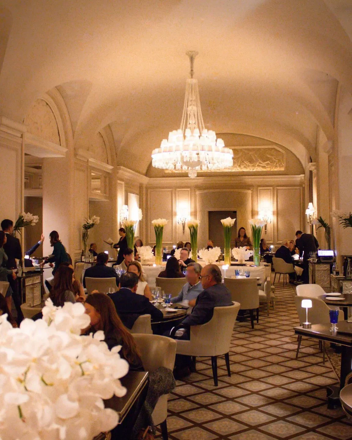 Elegant interior of Le George restaurant in Paris, with crystal chandelier and guests dining.