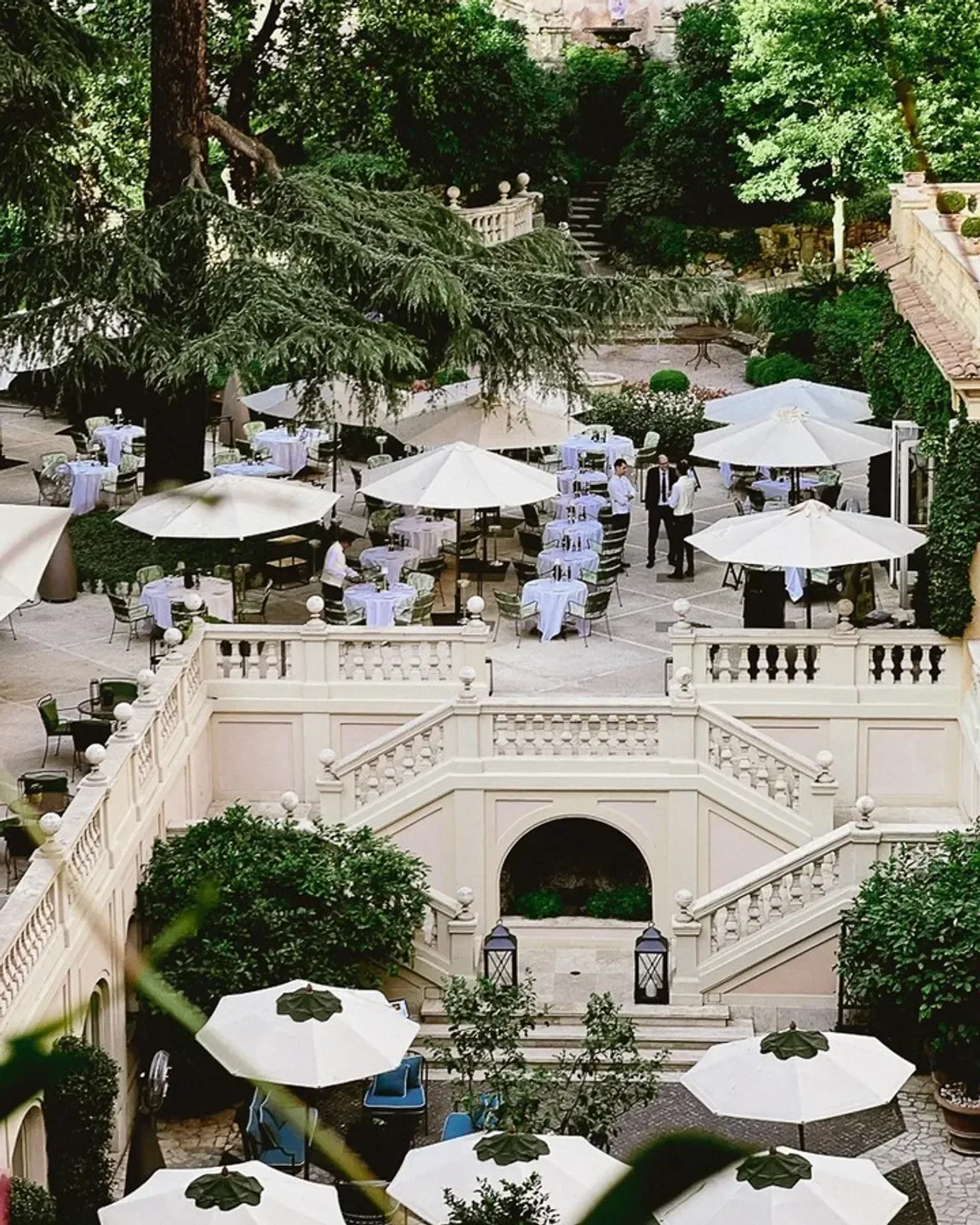 Outdoor dining at Le Jardin de Russie, Rome, with tables, umbrellas, and lush greenery.