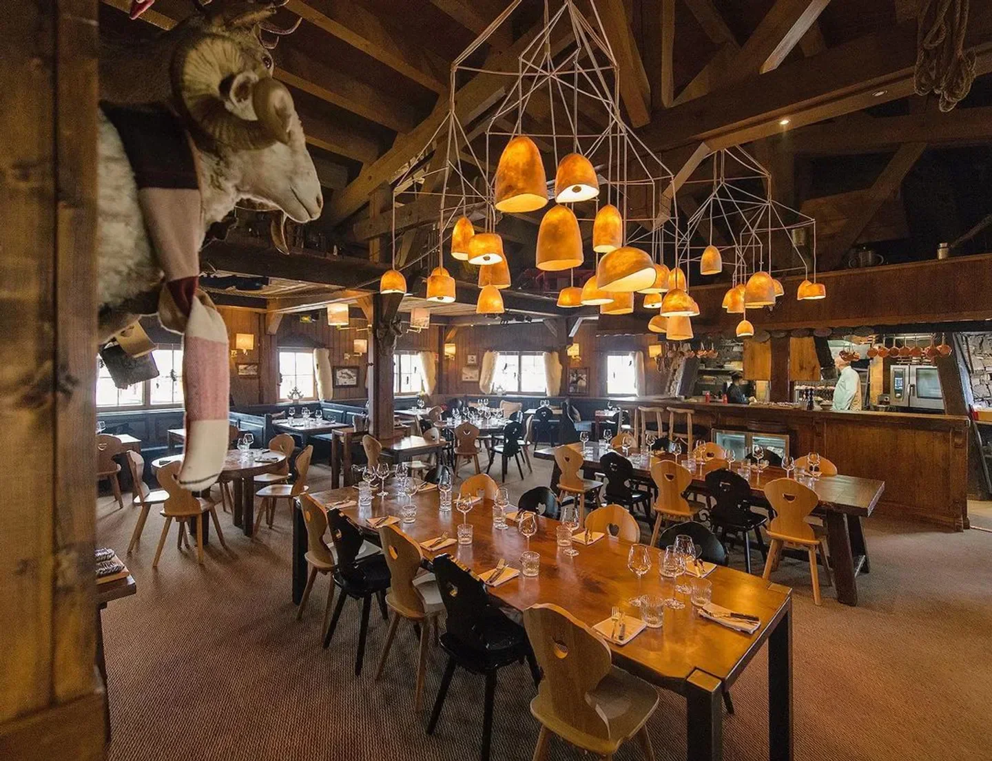 Cozy interior of Le Panoramic restaurant in Tignes, with wooden tables and unique lighting fixtures.