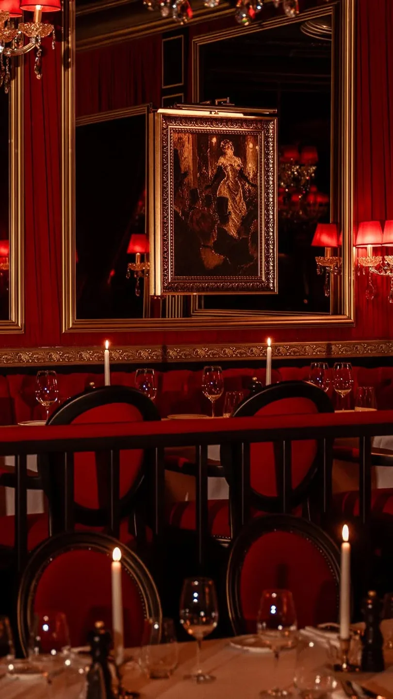 Le Piaf restaurant interior with plush red seating, golden mirrors, and candlelit tables in the city.