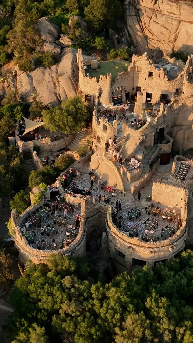 Le Terrazze Ritual restaurant exterior in Porto Cervo, built into a rocky hillside overlooking trees.