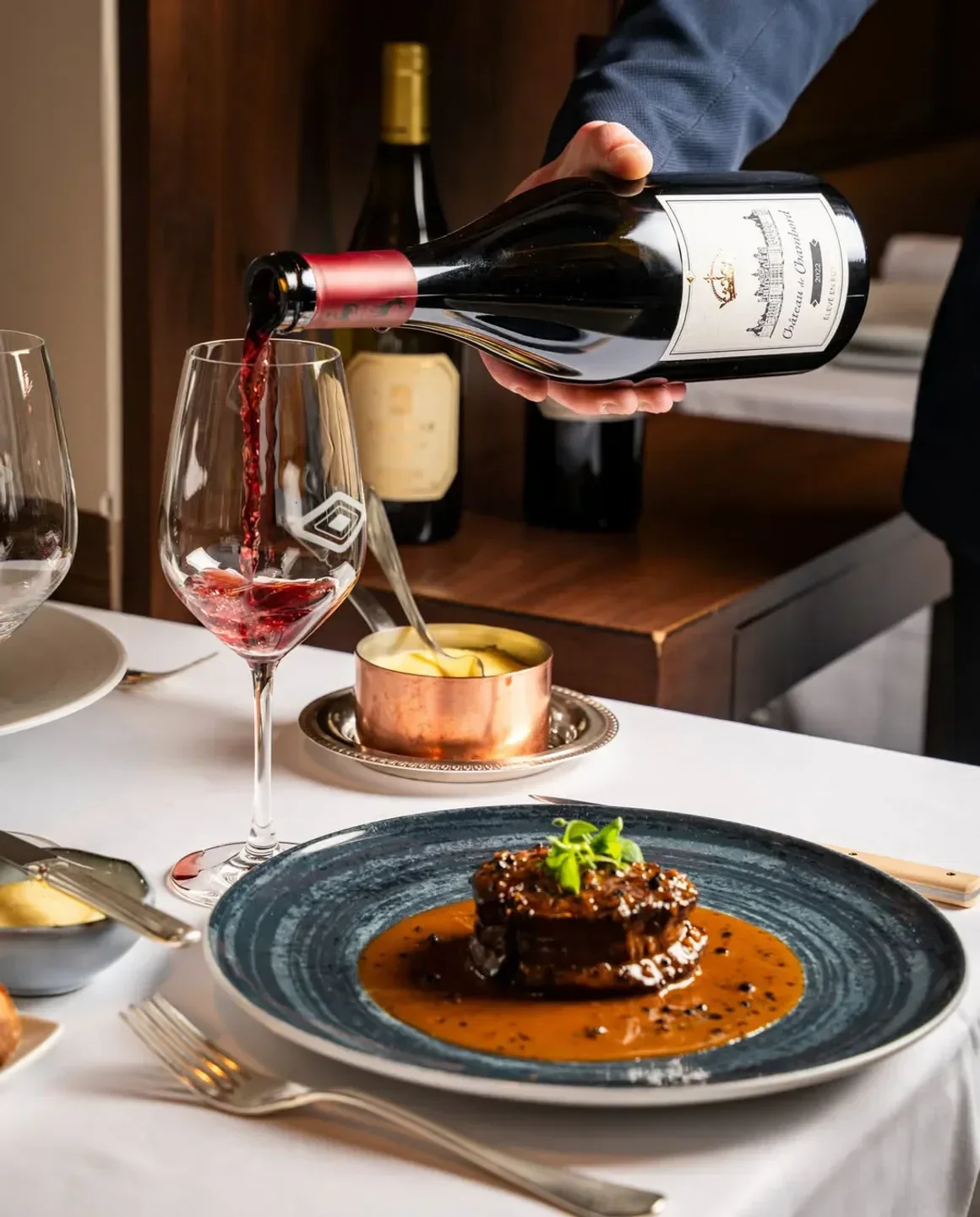 Fine dining at Le Violon d'Ingres in Paris: wine being poured, gourmet dish served.