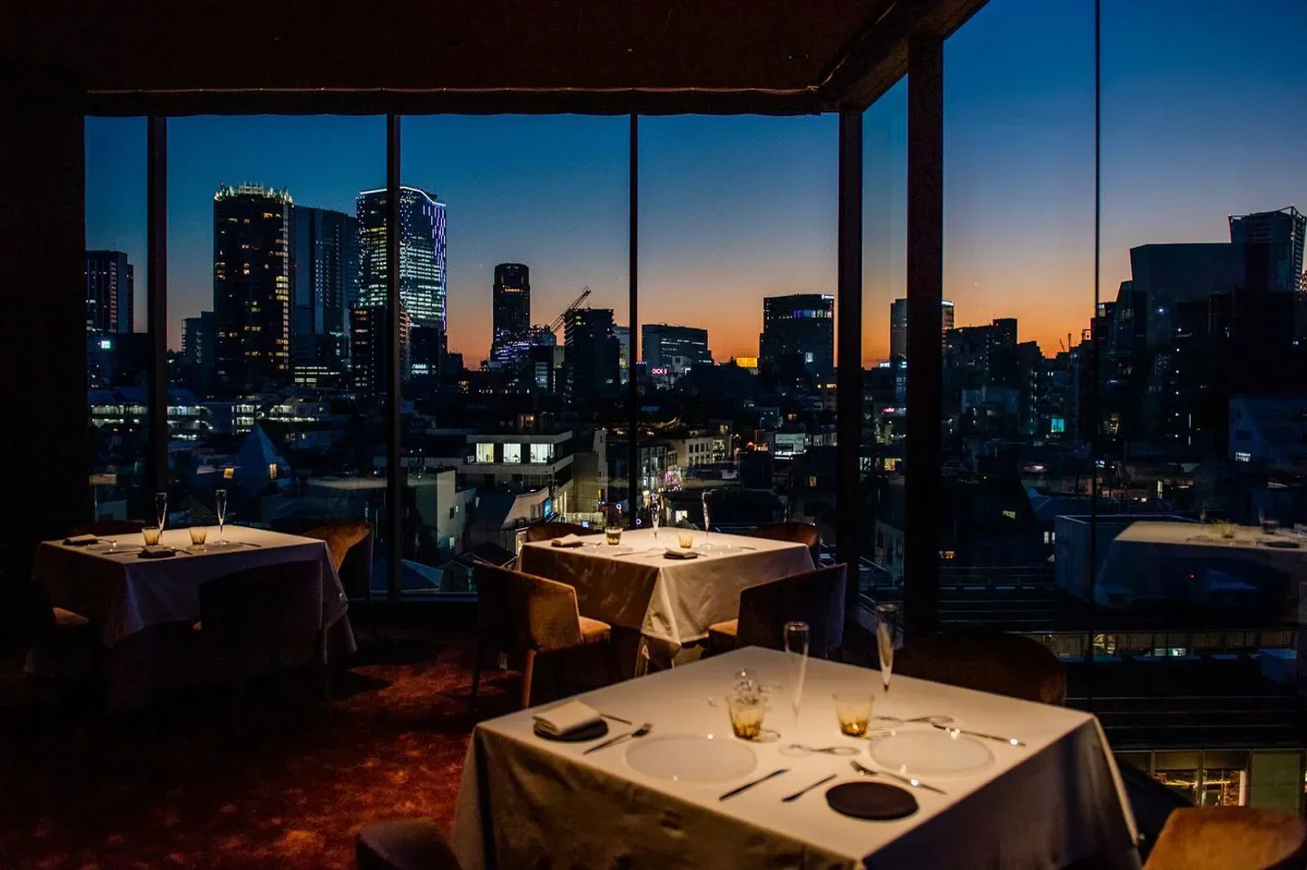 Elegant dining at l'élan, Tokyo, with city views at dusk, showcasing the restaurant.