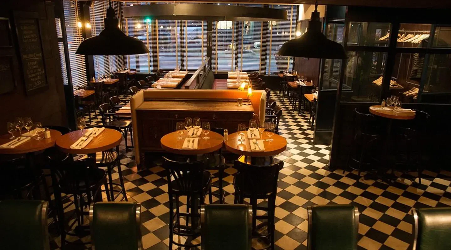 Cozy interior of Les Cavistes restaurant in Montreal, with round tables and checkered floor.